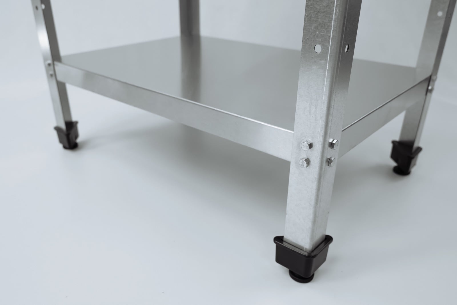 Нижняя полка и регулируемые ножки кухонного стеллажа.